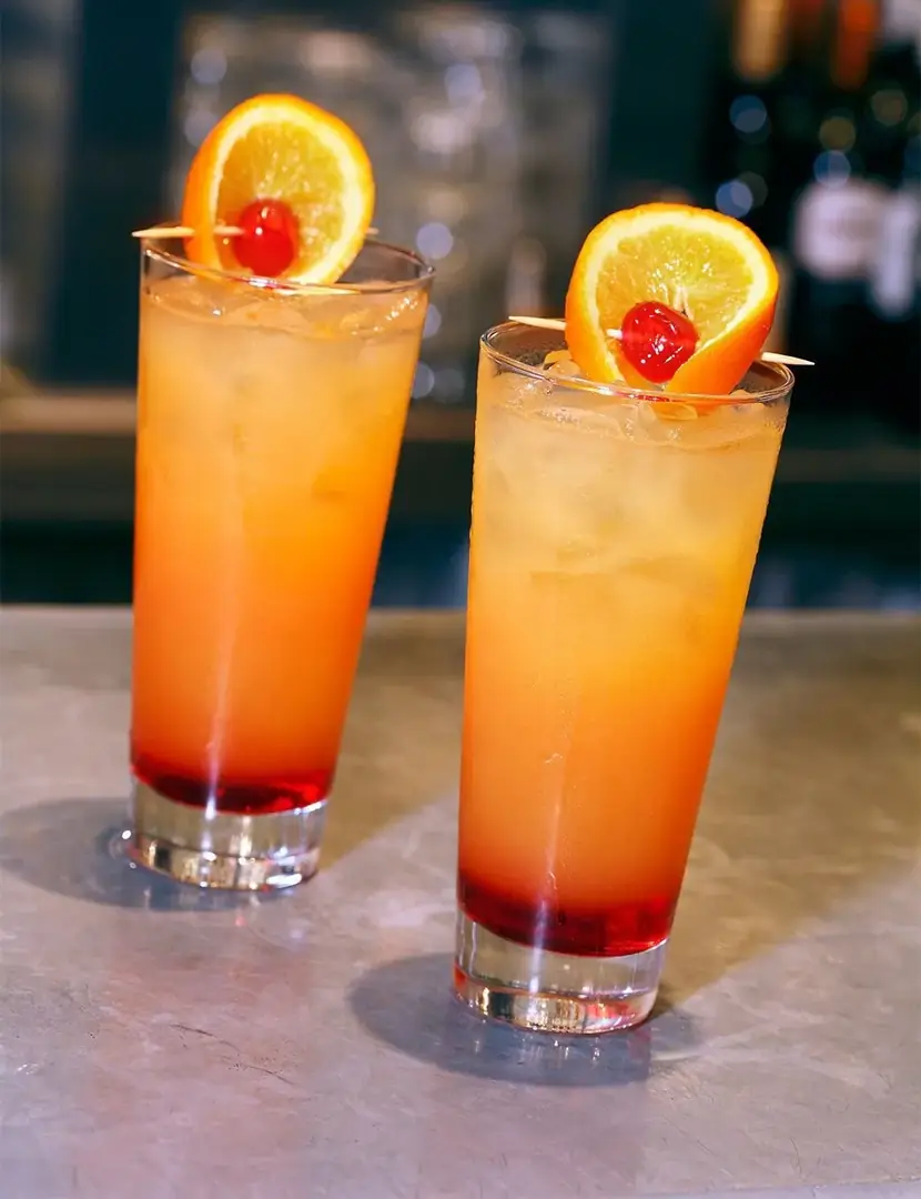 Dos cócteles naranja con rodaja de naranja y cereza