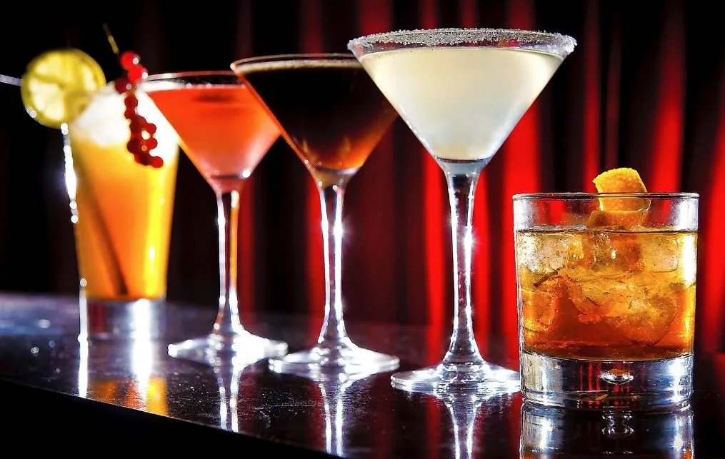 Copas de martini y cócteles sobre una barra iluminada