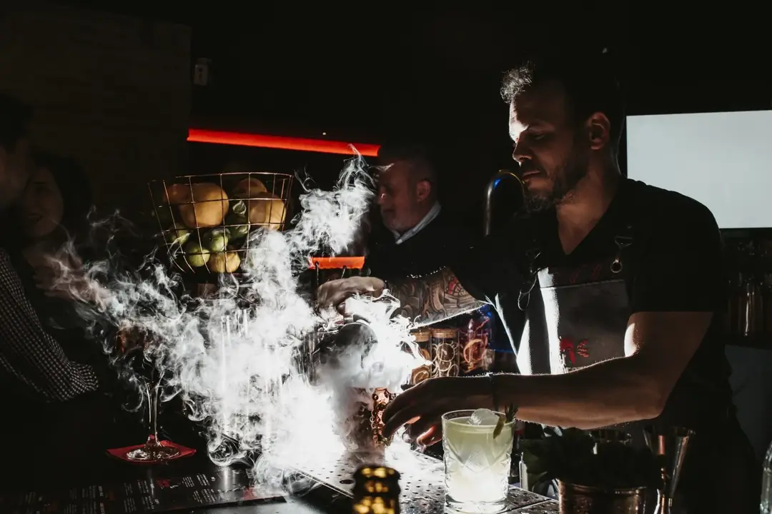 Bartender preparando un cóctel con humo detrás de la barra