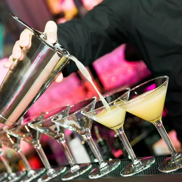 Bartender sirviendo varias copas de martini a la vez
